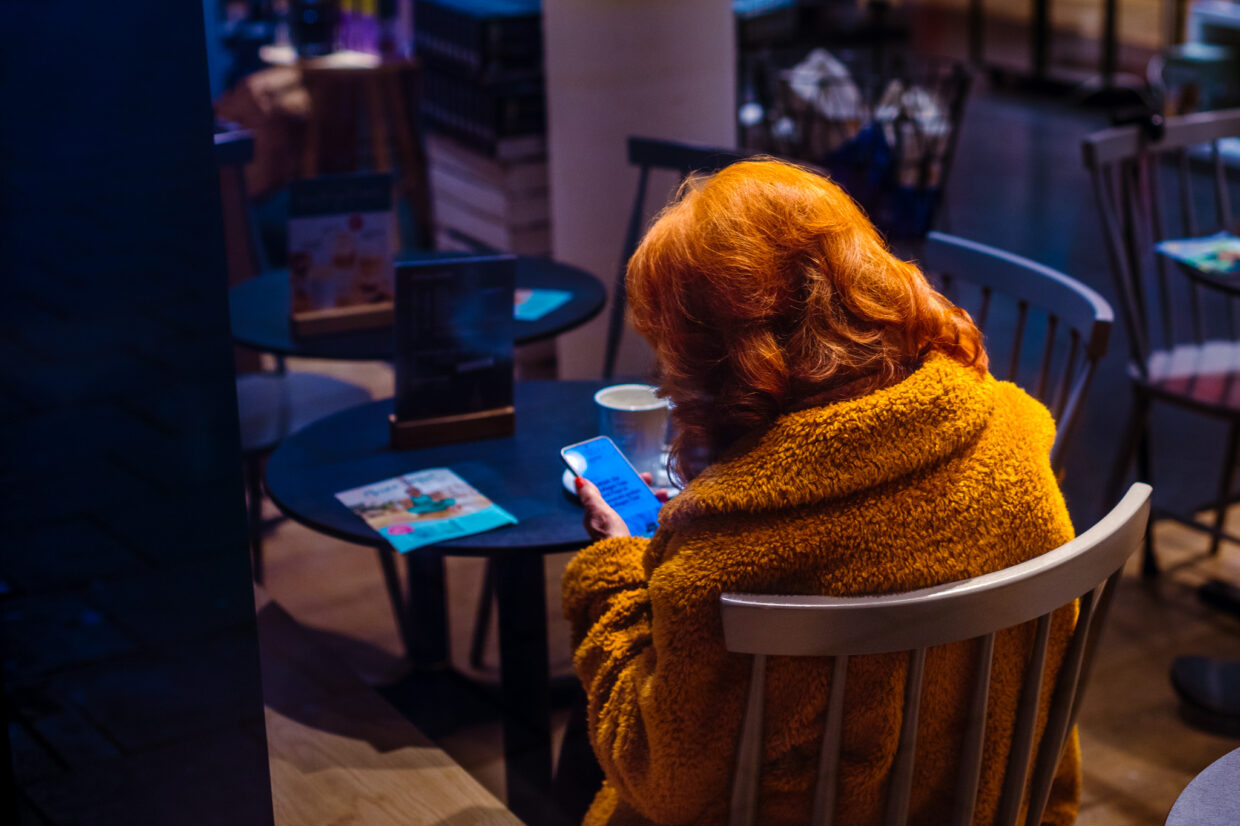 Eine Dame in einem Cafe an ihrem Smartphone