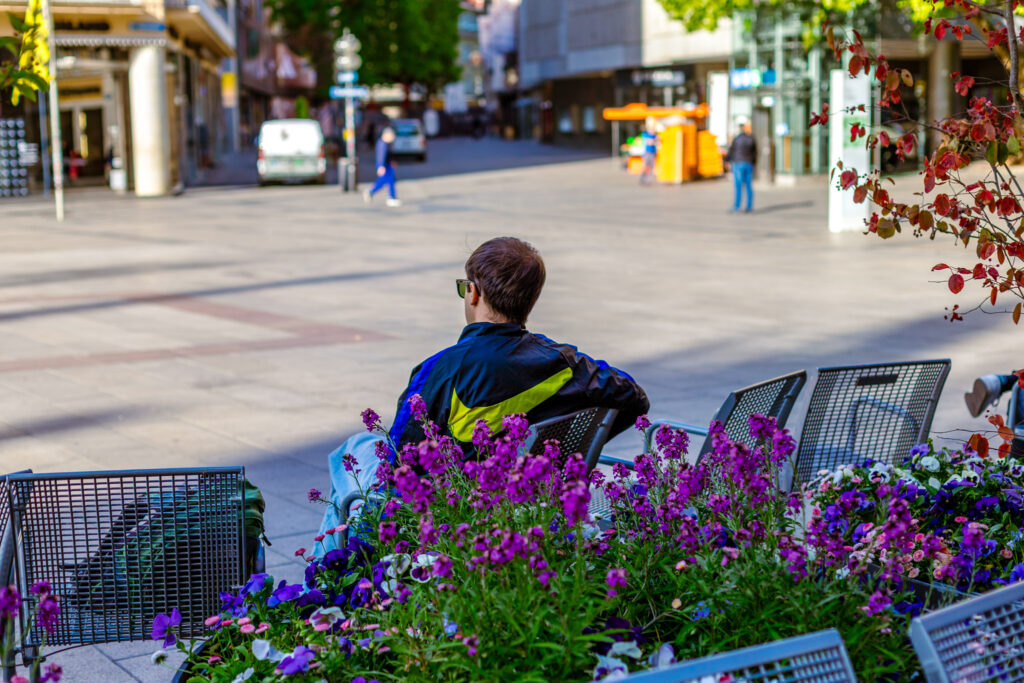 Eine Person sitzt auf einer Bank am Marienplatz in München